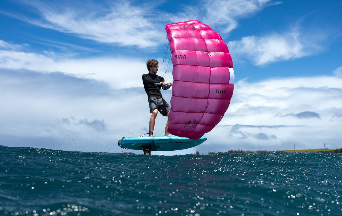 Person with a parawing on water with a pink parawing and blue board.